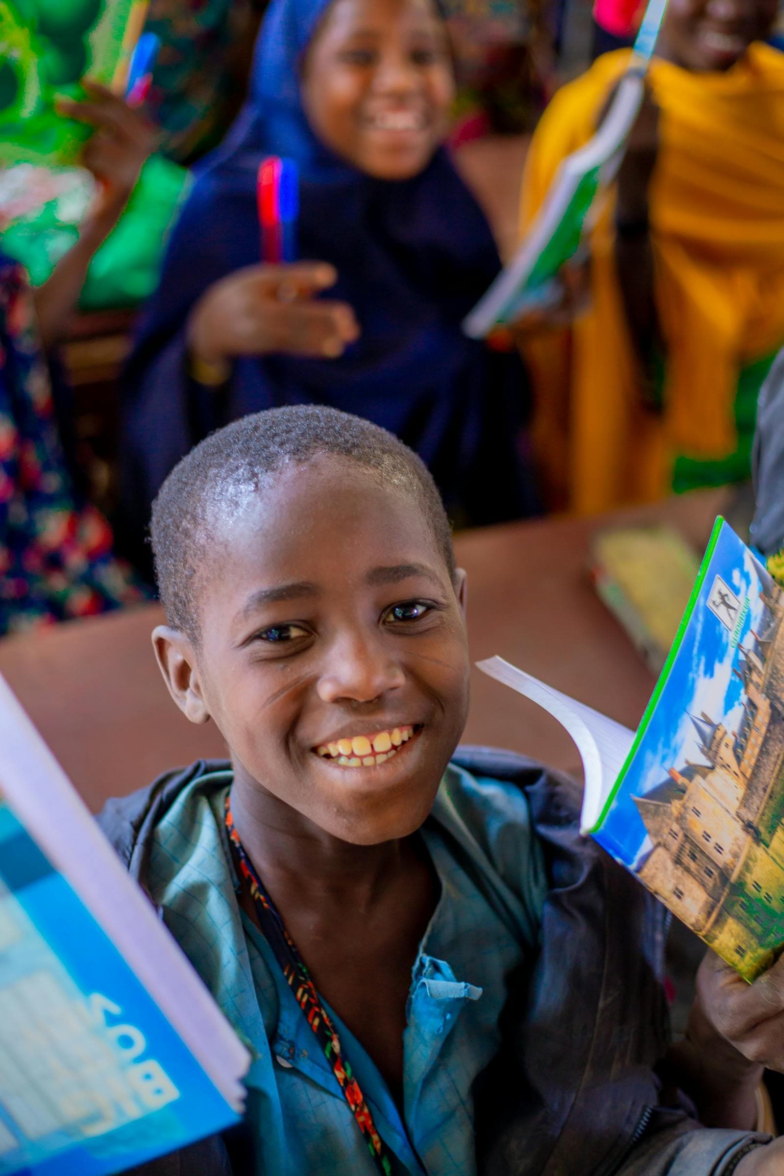 School children smiling and holding colourful notebooks and pens